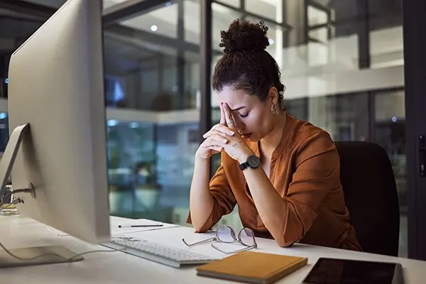 Femme fatiguée devant son ordinateur, le soir au bureau